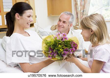 Stock Photograph - Young Girl Giving Flowers To Her Mother In Hospital. Fotosearch