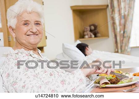 Stock Image - Young Woman Eating Hospital Food. Fotosearch