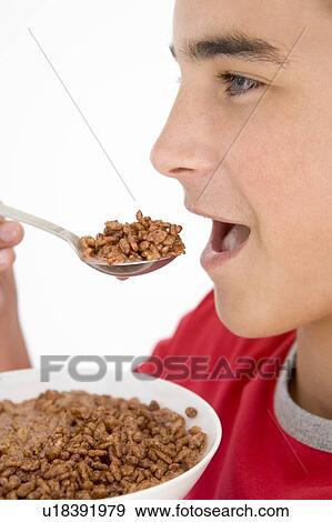 Stock Photo - Boy eating chocolate puff cereal. Fotosearch