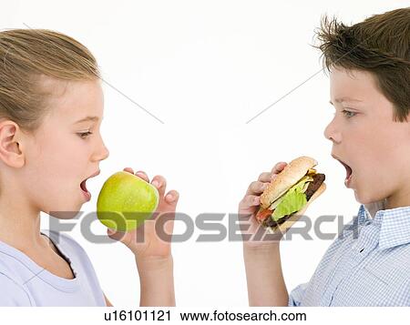 Sister eating apple by brother eating cheeseburger View Large Photo Image Stock Image - Sister eating apple by brother eating cheeseburger. Fotosearch