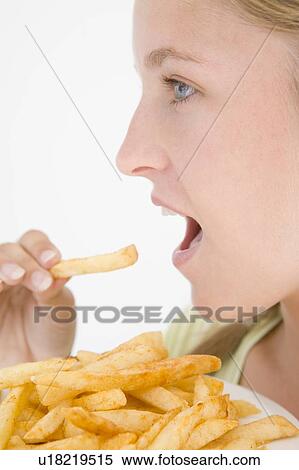 Stock Photography - Teenage girl eating French fries. Fotosearch