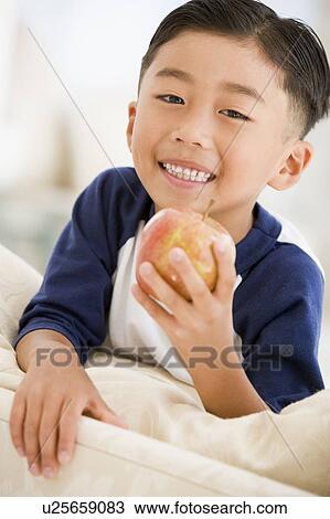 Young boy eating apple in living room smiling View Large Photo Image Stock Image - Young boy eating apple in living room smiling. Fotosearch
