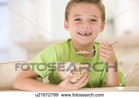 Young boy eating cereal in living room smiling View Large Photo Image Stock Photo - Young boy eating cereal in living room smiling. Fotosearch