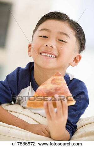 Young boy eating pizza slice in living room smiling View Large Photo Image Stock Image - Young boy eating pizza slice in living room smiling. Fotosearch