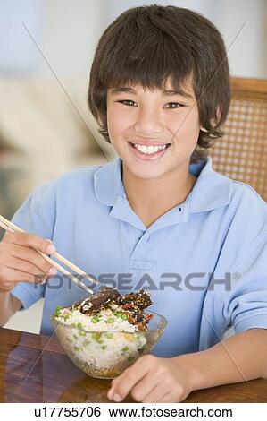 Young boy in dining room eating chinese food smiling View Large Photo Image Stock Photograph - Young boy in dining room eating chinese food smiling. Fotosearch