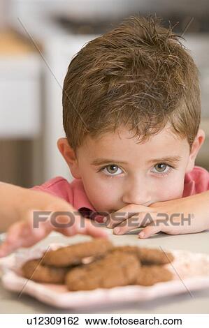 Young boy in kitchen eating cookies View Large Photo Image Stock Image - Young boy in kitchen eating cookies. Fotosearch