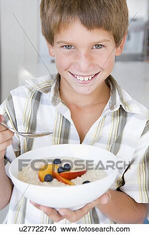 Young boy in kitchen eating oatmeal with fruit smiling View Large Photo Image Stock Image - Young boy in kitchen eating oatmeal with fruit smiling. Fotosearch