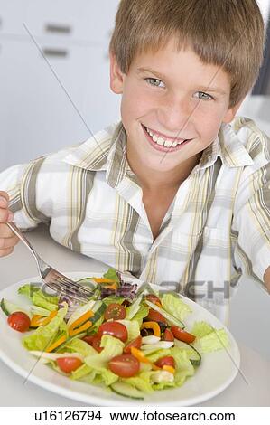Young boy in kitchen eating salad smiling View Large Photo Image Picture - Young boy in kitchen eating salad smiling. Fotosearch