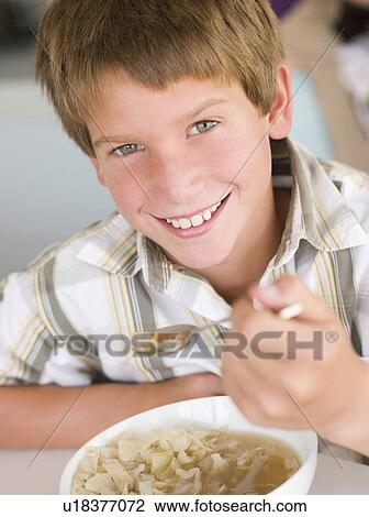 Young boy in kitchen eating soup and smiling View Large Photo Image Stock Image - Young boy in kitchen eating soup and smiling. Fotosearch