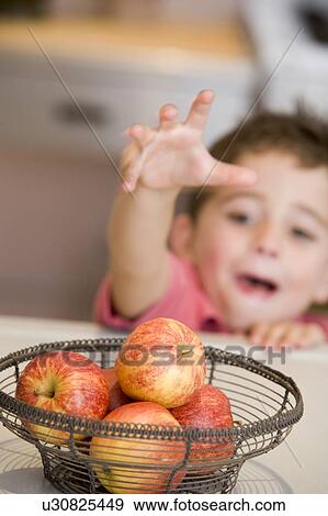 Young boy in kitchen getting apple off counter View Large Photo Image Stock Photo - Young boy in kitchen getting apple off counter. Fotosearch