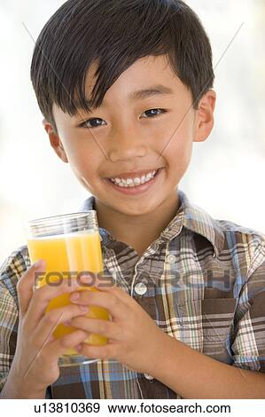 Young boy indoors drinking orange juice smiling View Large Photo Image Stock Photo - Young boy indoors drinking orange juice smiling. Fotosearch