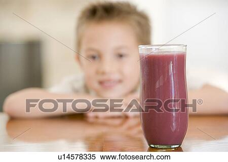 Stock Photography - Young boy indoors with focus on juice glass. Fotosearch