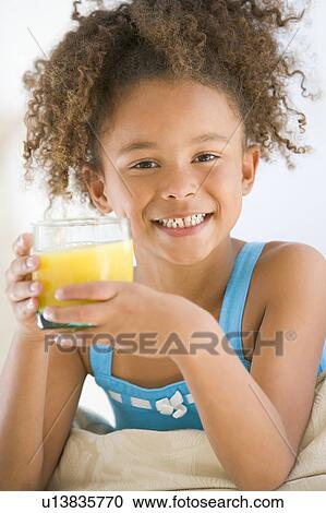 Young girl drinking orange juice in living room smiling View Large Photo Image Stock Image - Young girl drinking orange juice in living room smiling. Fotosearch