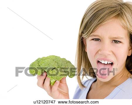 Young girl holding broccoli and sticking tongue out View Large Photo Image Stock Photo - Young girl holding broccoli and sticking tongue out. Fotosearch