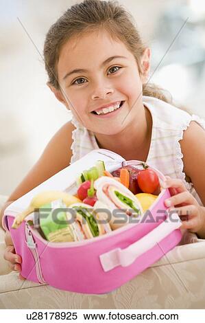 Young girl holding packed lunch in living room smiling View Large Photo Image Stock Photography - Young girl holding packed lunch in living room smiling. Fotosearch