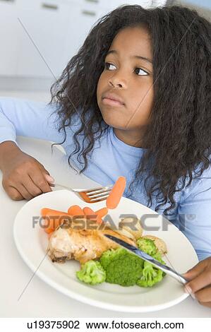 Young girl in kitchen eating chicken and vegetables View Large Photo Image Stock Image - Young girl in kitchen eating chicken and vegetables. Fotosearch