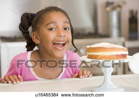 Young girl in kitchen looking at cake on counter smiling View Large Photo Image Picture - Young girl in kitchen looking at cake on counter smiling. Fotosearch