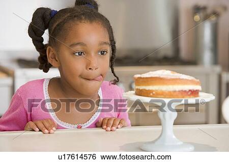 Young girl in kitchen looking at cake on counter View Large Photo Image Stock Photograph - Young girl in kitchen looking at cake on counter. Fotosearch