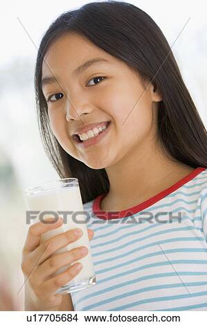 Picture - Young girl indoors drinking milk smiling. Fotosearch