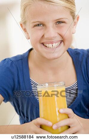 Young girl indoors drinking orange juice smiling View Large Photo Image Picture - Young girl indoors drinking orange juice smiling. Fotosearch