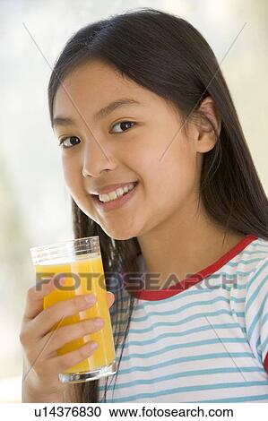 Young girl indoors drinking orange juice smiling View Large Photo Image Stock Image - Young girl indoors drinking orange juice smiling. Fotosearch
