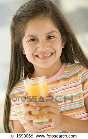 Young girl indoors drinking orange juice smiling View Large Photo Image Stock Photography - Young girl indoors drinking orange juice smiling. Fotosearch