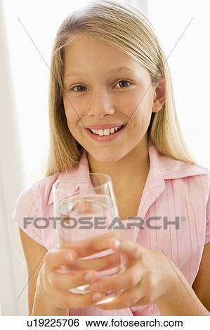 Stock Photograph - Young girl indoors drinking water smiling. Fotosearch