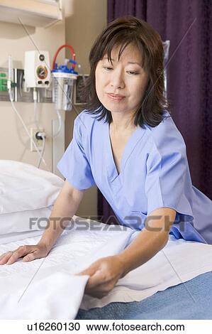 Stock Image - A Nurse Making A Bed In A Hospital Ward. Fotosearch