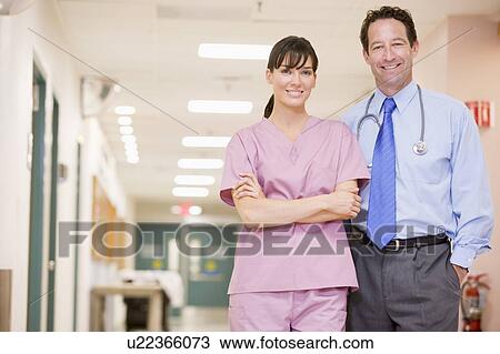 Stock Image - Doctor And Nurse Standing In A Hospital Corridor. Fotosearch