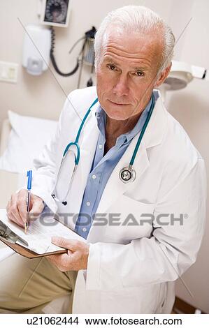 Middle Aged Doctor Writing On His Clipboard View Large Photo Image Picture - Middle Aged Doctor Writing On His Clipboard. Fotosearch