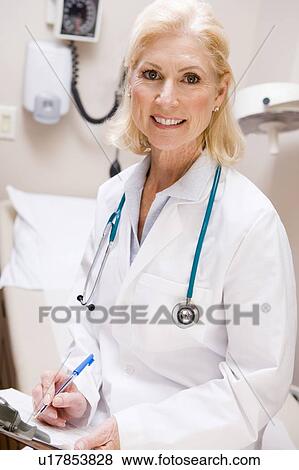 Stock Photo - Middle Aged Female Doctor Writing On A Clipboard. Fotosearch