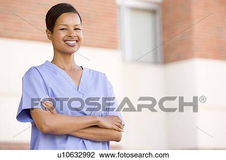 Stock Image - Nurse Standing Outside A Hospital. Fotosearch