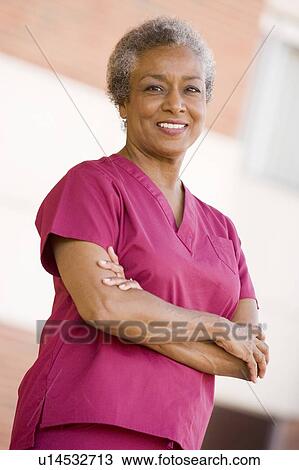 Stock Image - Nurse Standing Outside A Hospital. Fotosearch