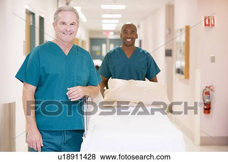 Two Orderlies Pushing An Empty Bed Down A Hospital Corridor View Large Photo Image Stock Photo - Two Orderlies Pushing An Empty Bed Down A Hospital Corridor. Fotosearch