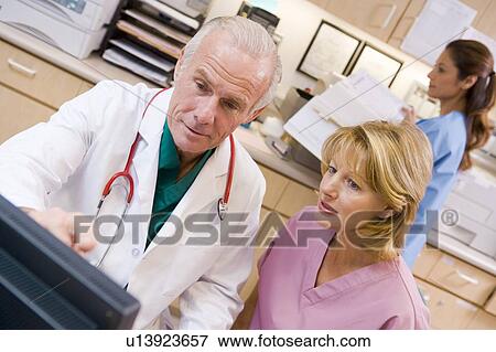 Stock Photo - A Doctor And Nurse Discussing Something At The Reception Area Of A Hospital. Fotosearch