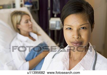 Stock Image - Doctor Looking Serious, Standing In Hospital Room. Fotosearch