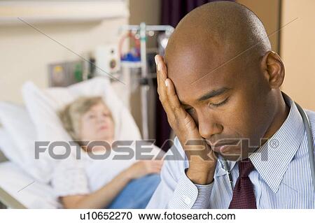 Stock Image - Doctor Looking Tired And Frustrated In Hospital Room. Fotosearch