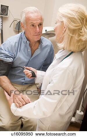 Stock Image - Doctor Measuring Mans Blood Pressure. Fotosearch