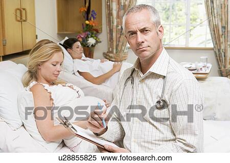 Doctor sitting by pregnant women holding chart View Large Photo Image Stock Photography - Doctor sitting by pregnant women holding chart. Fotosearch