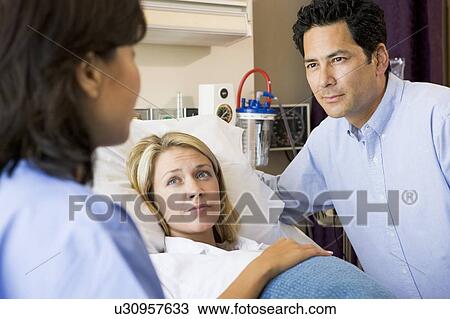 Stock Image - Doctor Talking To Pregnant Woman And Her Husband. Fotosearch