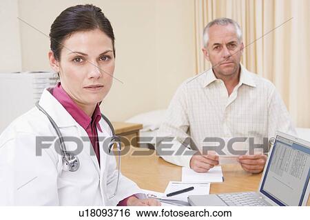 Stock Photograph - Doctor with laptop and man in doctor's office frowning. Fotosearch