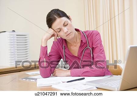 Stock Image - Doctor with laptop sleeping in doctor's office. Fotosearch