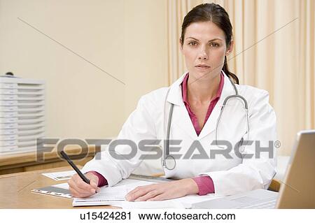 Stock Image - Doctor with laptop writing in doctor's office. Fotosearch