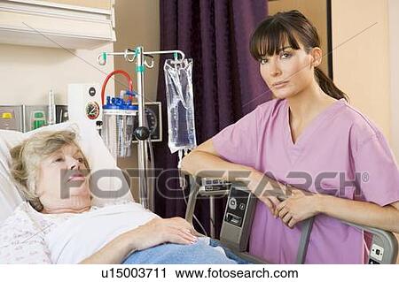 Stock Image - Nurse Checking Up On Patient Lying In Hospital Bed. Fotosearch
