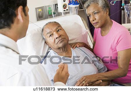 Stock Image - Senior Couple Talking To Doctor, Looking Worried. Fotosearch