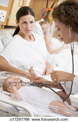 Stock Photograph - Doctor checking baby's heartbeat with new mother watching. Fotosearch