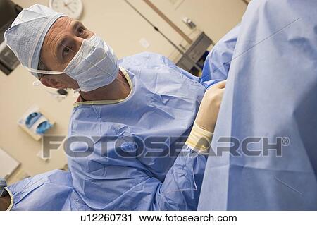 Stock Image - Doctor conducting with egg retrieval procedure. Fotosearch