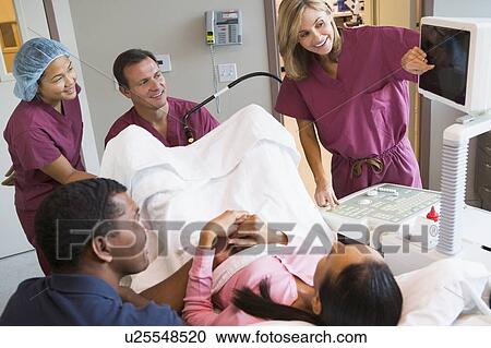 Stock Image - Doctor looking at monitor while retrieving eggs from ovary using vaginal ultrasound. Fotosearch