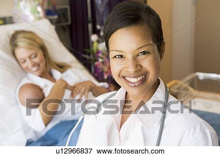 Stock Photo - Doctor Standing In Her Patients Room, Woman Holding Baby. Fotosearch