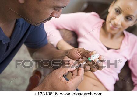Stock Photograph - Man helping woman inject drugs to gain pregnancy (selective focus). Fotosearch